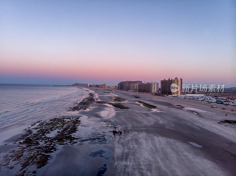 Puerto的沙滩Peñasco Resort Mexican Town at Dusk与各种各样的酒店在远处和很少的人